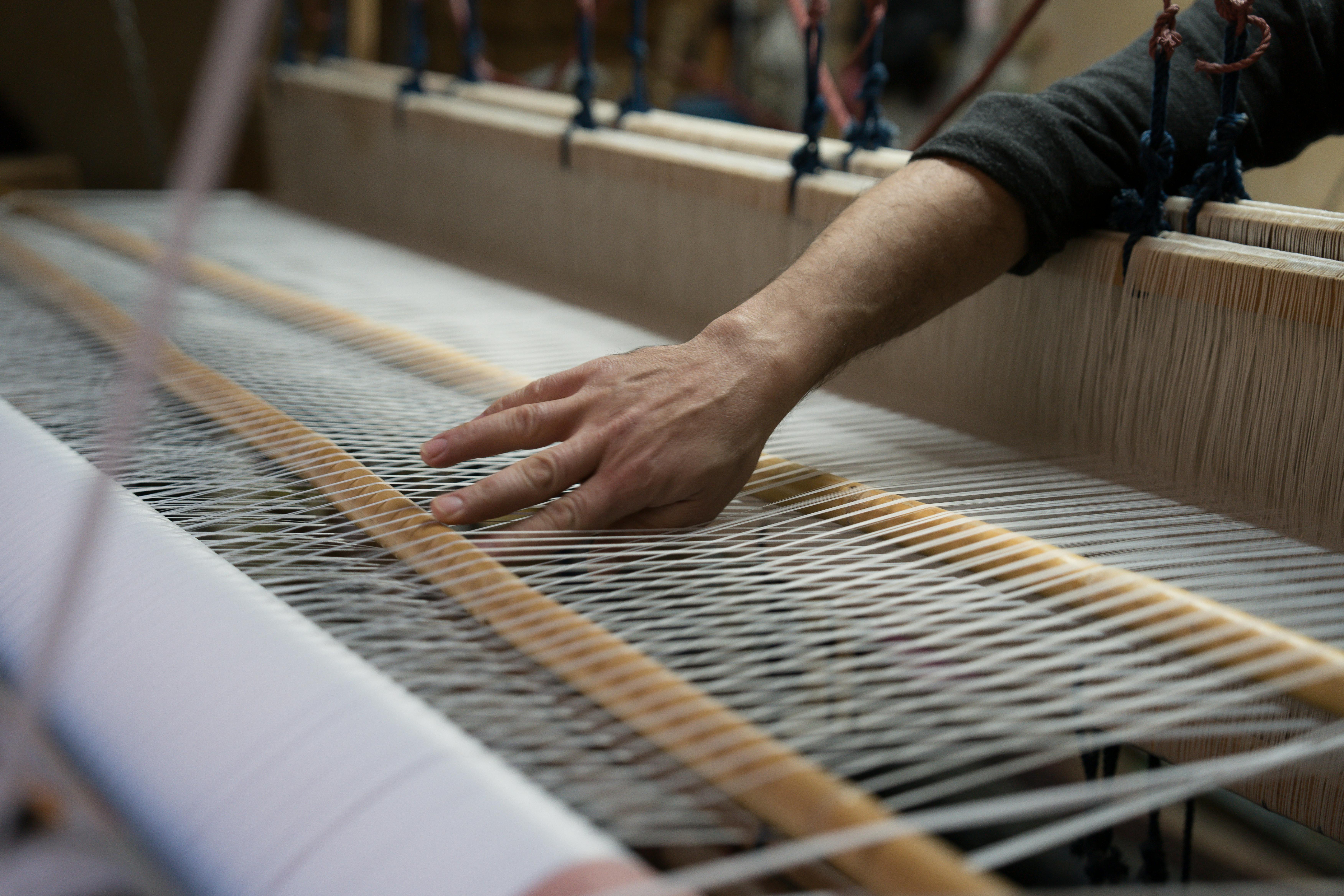 Close-up of artisan hands working on intricate loom with detailed thread patterns