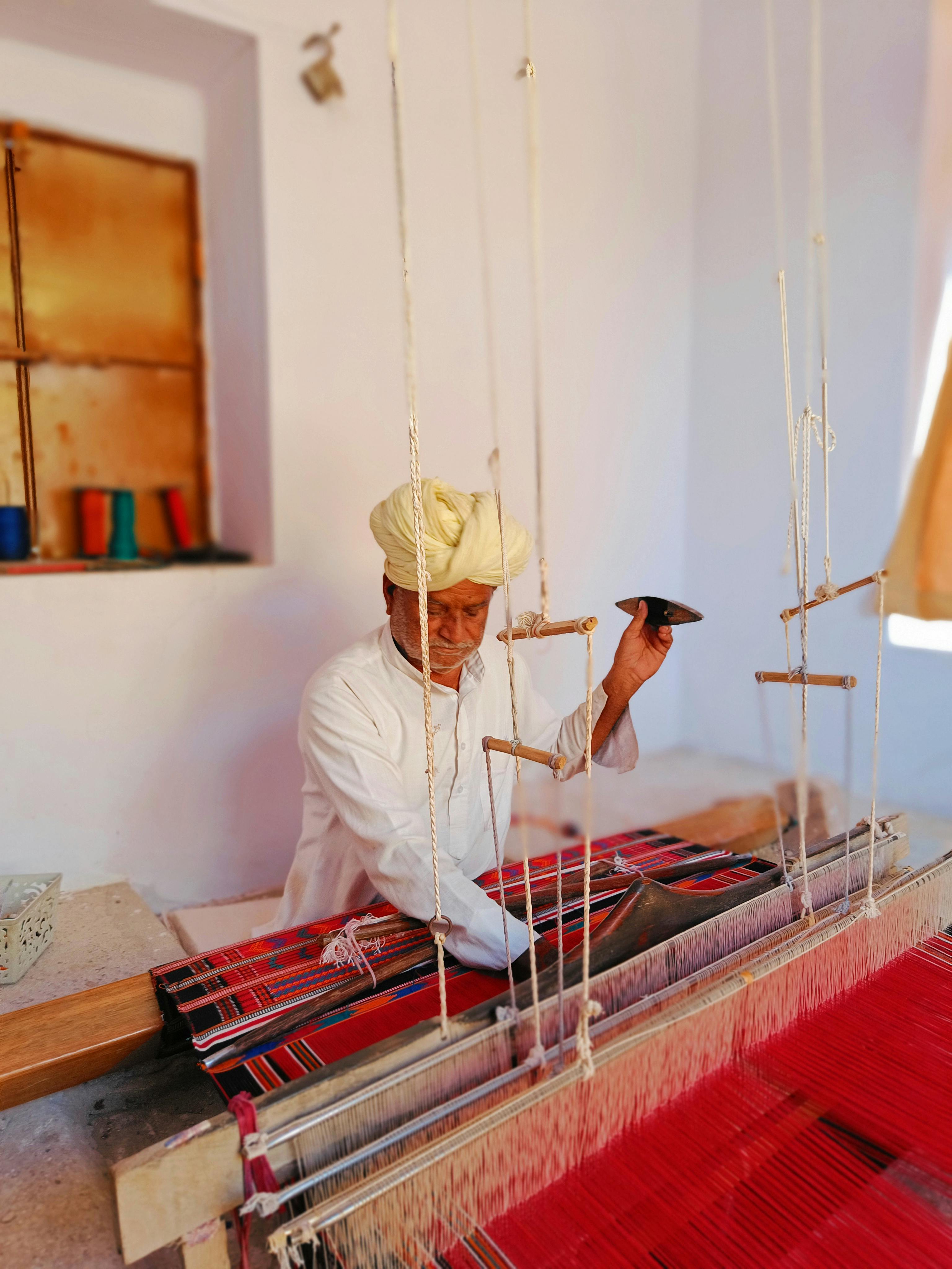 Master weaver working on traditional loom with red patterned textile